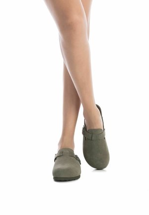 Zuecos de color verde oliva hechos de ante con una textura suave, que presentan una correa decorativa y un acento de hebilla. Diseño de punta redondeada y suela plana.