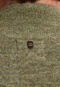 Olivengrøn strikket sweater med høj krave og et struktureret mønster. Har et sort mærke med guldtekst "PME LEGEND" bagpå.