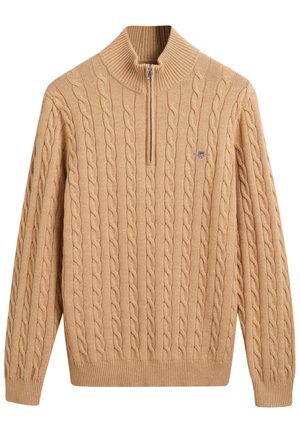 Beige cable-knit sweater with a high collar and half-zip closure. Features ribbed cuffs and hem, with a small logo on the chest.