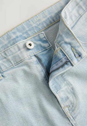 Világoskék, slim fit farmernadrág, cipzárral, fém gombos záródással és kontrasztos varrással. Az anyaga puha tapintású.