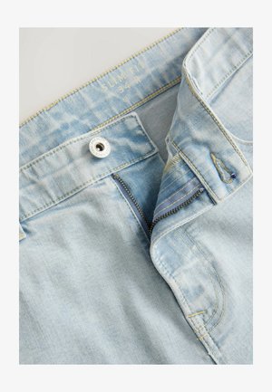 Lichtblauwe denim jeans met een slim fit, voorzien van een rits, metalen knoopsluiting en contrasterende stiksels. De stof heeft een zachte textuur.