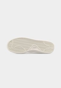 Σόλα λευκού παπουτσιού Nike με σχέδιο σκάλισμα ψαροκόκαλου και λογότυπο Nike στο κέντρο, σε απλό ανοιχτό φόντο.