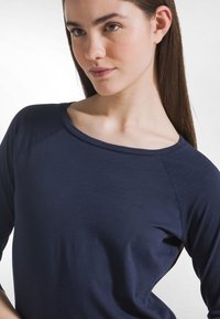Granatowy, długi rękaw top wykonany z miękkiego, gładkiego materiału. Posiada szeroki dekolt i rękawy raglanowe zapewniające luźne dopasowanie.