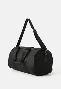 Čierna taška cez plece vyrobená z textúrovanej tkaniny. Obsahuje dvojité uši, nastaviteľný ramenný popruh a zips na uzatvorenie. Elegantný, valcovitý dizajn.