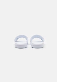 Hvide flip-flops med bløde, flade såler og buede stropper. Materialet ser glat ud uden mønstre eller detaljer.