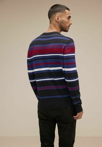 Stickad rundhalsad tröja med horisontella ränder i burgundy, blått och vitt på en svart bakgrund, med ribbade muddar och nederkant.