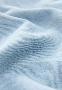 Tissu bleu clair avec une texture fine tissée et des plis doux créant des ombres et des reflets délicats.