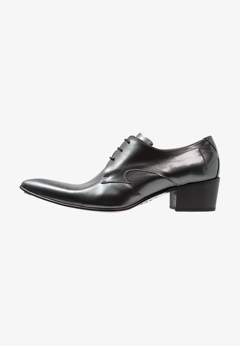 Chaussure habillée en cuir noir poli avec bout pointu, fermeture à lacets et talon bloc empilé, vue de côté.