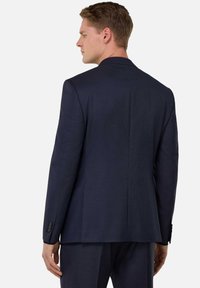 Navy blue, tailored suit jacket with a smooth texture, notch lapels, and a single vent at the back. Buttoned cuffs and fitted design.