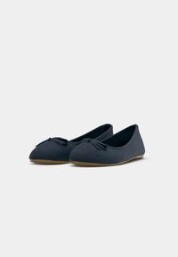 Ballerine blu navy in morbida suede, con punta arrotondata e un piccolo fiocco sul davanti. Suola flessibile per comfort.