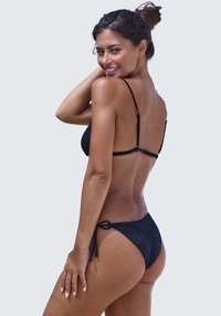 Black bikini set featuring a ribbed texture, adjustable straps, and a tie-side bottom. The design emphasizes a minimal coverage style.