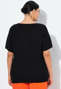 Černý, oversized pletený svetr s širokým výstřihem a krátkými rukávy, nabízející uvolněný střih. Hladká textura, minimalistický design.