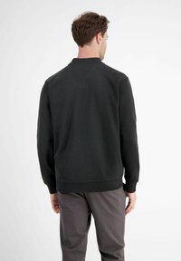 Black sweatshirt with a rounded collar, ribbed cuffs and hem, made of soft material. The back view shows a clean, minimalistic design.