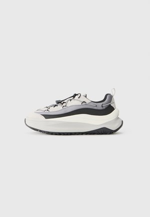 Sneakers med et lagdelt design i lysegrått, svart og hvitt. Har strukturert overdel, elastiske lisser og en tykk, strukturert såle.
