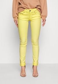 Gula denim skinny jeans med slim fit, uppvikta fållar och framfickor. Tyget verkar slätt och något elastiskt.