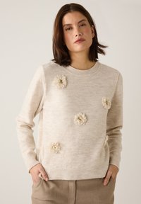 Pull beige clair à col rond, orné d'appliques florales texturées et d'un ourlet côtelé, conçu dans un matériau doux et duveteux.