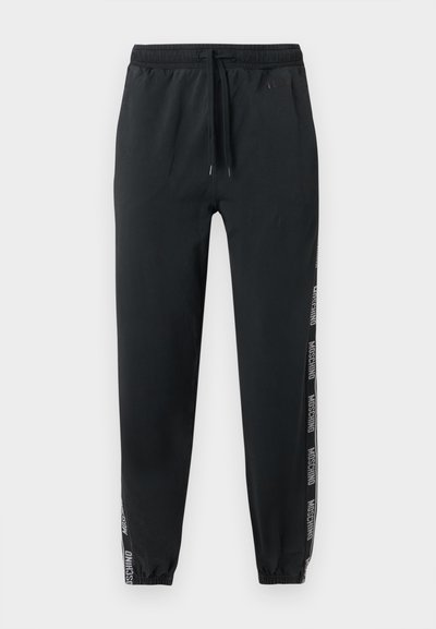 Μαύρο παντελόνι τζόγκερ με ελαστικές μανσέτες και ζώνη μέσης, διαθέτει κορδονάκι και λευκές ρίγες με το λογότυπο "Moschino" κατά μήκος των εξωτερικών πλευρών των ποδιών.