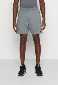 Pantalones cortos deportivos grises con cintura elástica, que presentan un logotipo negro en la parte inferior izquierda y una textura de tela suave.
