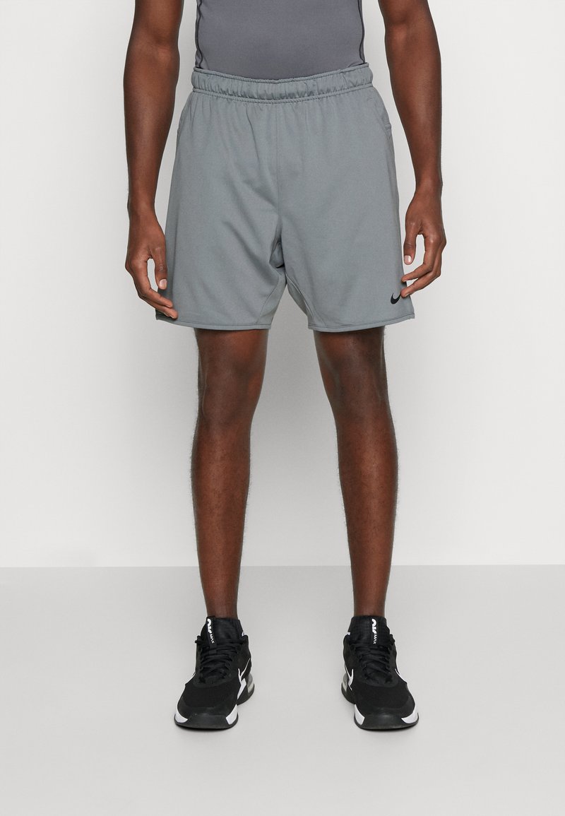 Pantalones cortos deportivos grises con cintura elástica, que presentan un logotipo negro en la parte inferior izquierda y una textura de tela suave.