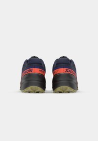 Men's running shoes in navy with red accents. Features textured fabric, rugged sole, and "Salomon" logo. Lightweight and cushioned design.