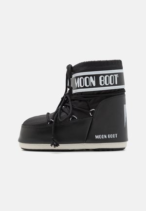 Black Moon Boot with a padded upper, secured by laces and a distinctive white band featuring the logo. Thick, textured rubber sole.