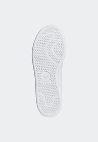 Semelle de basket blanche avec une adhérence texturée et à motifs. Présente une forme arrondie et un logo en relief. Finition du matériau lisse.