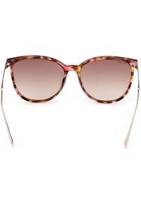Gafas de sol estilo cat-eye con un tinte degradado de marrón a rosa, montura con patrón de carey, patillas en tono dorado y textura suave.