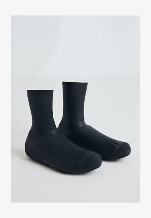 Bottines noires imperméables fabriquées en matériau lisse avec un ajustement serré, dotées d'une semelle en caoutchouc texturée pour une meilleure adhérence.