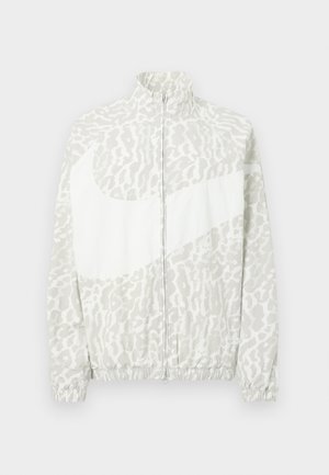 Jachetă ușoară în gri și alb, cu model leopard, guler înalt și manșete elastice cu un logo proeminent.