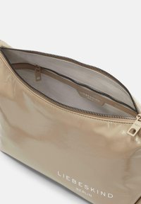 Pochette beige lucida con chiusura a zip, dotata di un'etichetta interna con il marchio. Materiale liscio con un design semplice.