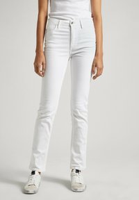 Vita denim skinny jeans med medelhög midja, femfickorsdesign och subtila sömmar. Pairad med vita sneakers, vilket visar en avslappnad look.