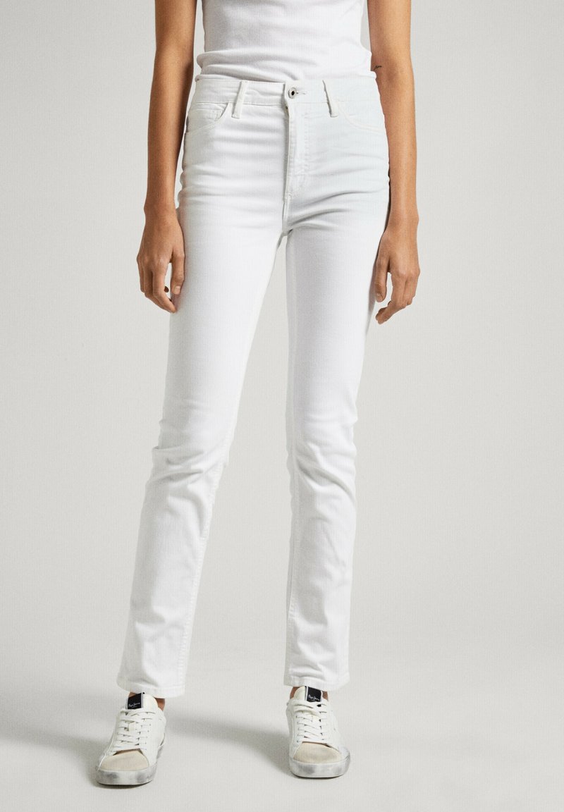 Vita denim skinny jeans med medelhög midja, femfickorsdesign och subtila sömmar. Pairad med vita sneakers, vilket visar en avslappnad look.