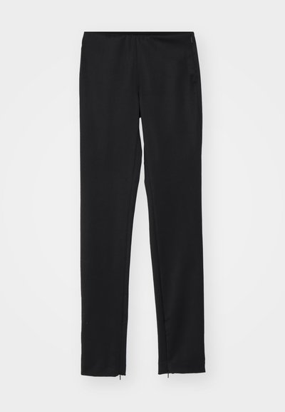 Mustat, kapeat housut elastisella vyötäröllä, sileä pinta ja vetoketjuyksityiskohdat helmassa. Valmistettu kevyestä kankaasta.