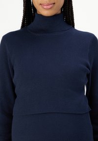 Maglione girocollo a coste di colore blu navy con design cropped. Caratterizzato da una texture morbida e una silhouette aderente, con collo alto e maniche lunghe.