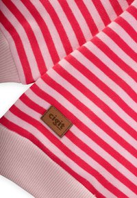 Tessuto a righe rosso e rosa con texture a coste; presenta un'etichetta in pelle marrone con il logo "cigit" cucito sul materiale.