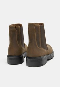 Hnedé kožené členkové čižmy s elastickými bočnými panelmi, textúrovaným povrchom a hrubou čiernou gumovou podrážkou s dezénom.