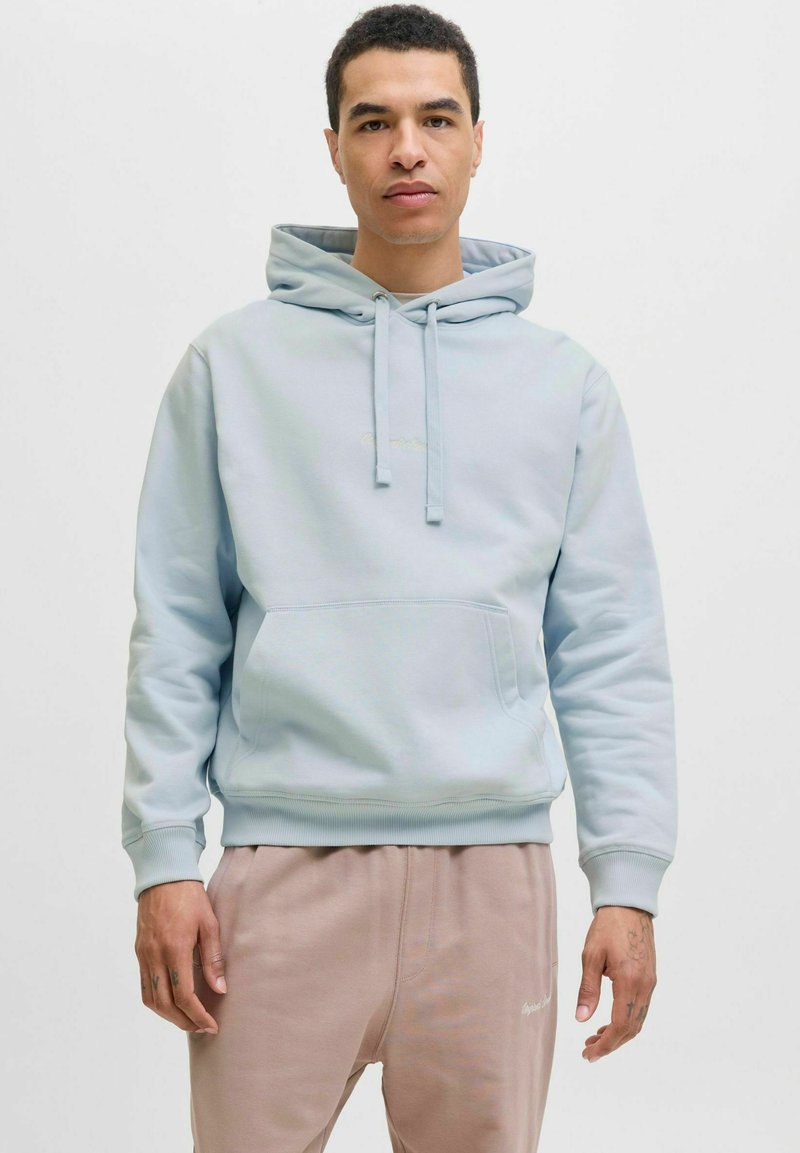 Hoodie de algodón azul claro con un bolsillo frontal, capucha con cordón y dobladillo acanalado. Llevado con pantalones de chándal rosa claro que presentan un logo.