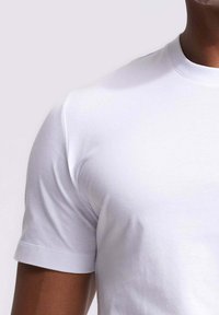 Witte katoenen t-shirt met korte mouwen, ronde halslijn, gladde textuur en schone naden. Geen zichtbare logo's of patronen.