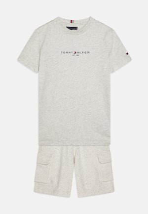 Šviesiai pilka medvilninė marškinėlių su trumpomis rankovėmis ir "TOMMY HILFIGER" logotipu. Suderinta su atitinkamais krovinių šortais, turinčiais dvi šonines kišenes.