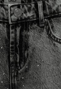 Czarne dżinsy z denimu, charakteryzujące się klasycznym pięciopunktowym fasonem, metalowym zapięciem na guzik oraz rozsypanymi ozdobami z rhinestonów na przodzie.