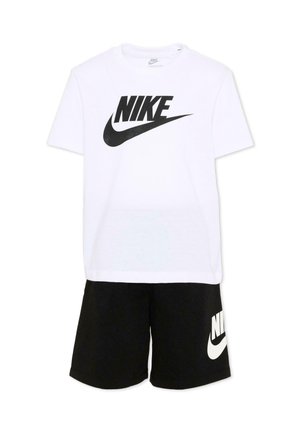Maglietta bianca Nike a maniche corte con grande logo nero abbinata a pantaloncini neri con logo Nike bianco sulla gamba sinistra.