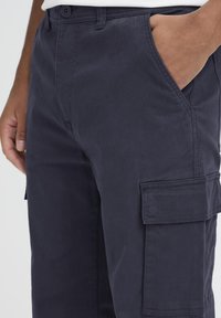 Navy hlače za tovor iz bombaža z gladko teksturo, ki imajo stranske žepe in zapiranje na gumb. Priložnostna zasnova z ohlapnim krojem.