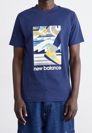 Tmavě modré bavlněné tričko s grafickým motivem abstraktních vln a žlutými teniskami. Má kulatý výstřih a krátké rukávy. Bílé nápis "new balance".