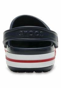Navy blue Crocs with white and red stripes, textured material, and a back strap featuring the brand name embossed in uppercase letters.