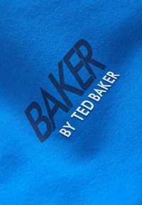 Blauwe katoenen stof met een gladde textuur heeft de tekst "BAKER" in vet zwart en "door TED BAKER" in kleinere witte letters.