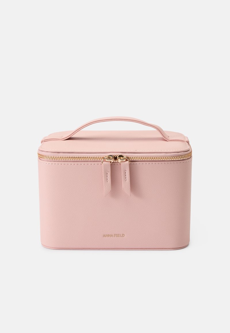 Estuche cosmético de imitación cuero rosa con forma rectangular, cremallera en tono dorado y asa en la parte superior; presenta el logo de la marca en la parte frontal.