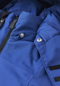 Blaue isolierte Jacke mit glatter Textur, Reißverschluss, Metallschnallen und schwarzen Klettverschluss-Akzenten an den Ärmeln. Sie verfügt über ein gepolstertes Design.