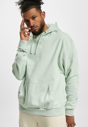 Minzgrüner Hoodie aus weichem Stoff, mit einer Fronttasche, gerippten Bündchen und Saum sowie Kapuze mit Kordelzügen. Einfaches, gesticktes Logo sichtbar.