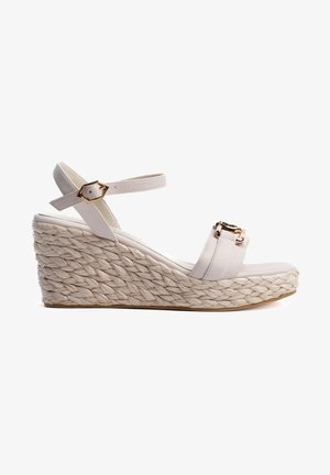 Sandale compensée avec une semelle en jute tressé, des brides en cuir beige clair et un accent en boucle dorée sur la bande avant.