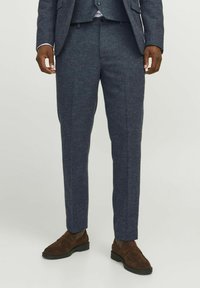 Dunkelblaue maßgeschneiderte Hose aus strukturiertem Stoff, mit geradem Schnitt, Seitentaschen und getragen mit braunen Wildleder-Loafers.